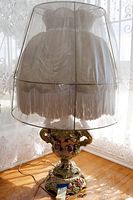 Full view of Capodimonte style ceramic table lamp with large ruffled fringe shade, showing overall design and shape.