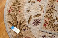 Close-up of floral border detail on beige rug showing woven texture and floral pattern in natural tones
