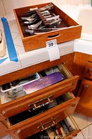 Overall view of wooden kitchen drawers with flatware tray on top and other utensils inside drawers.