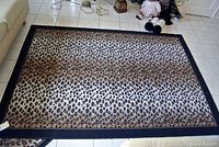 View of large leopard print area rug on tile floor, showing full pattern and border.