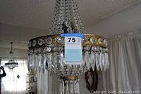 Side angle showing detailed crystal prisms hanging from gold-tone circular frame with faceted crystals embedded.