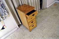Front view of the wooden side table with one drawer partially opened, showing wear and metal handles.