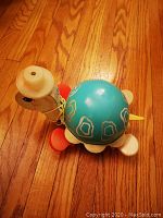Top angle view of the vintage turtle pull toy showing blue shell with yellow outlined patterns and white neck with yellow beak and painted eyes.