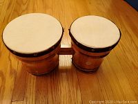 Angled side view of two connected wooden bongos showing drum heads, rims, and connecting piece with Mark II label.