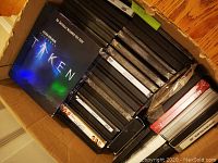Box with DVDs stacked, including Taken collection on top and other DVDs below