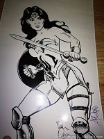 Full black and white Wonder Woman illustration showing dynamic pose, sword and shield, with artist signatures.