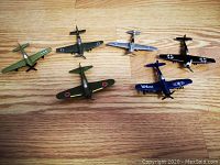 Six die-cast World War II model airplanes from 1982 in detailed paint and mint condition displayed on wooden floor.