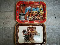 Two vintage Coca-Cola metal serving trays mounted vertically on a wall, one with a red border and picnic table scene, the other with a woodgrain border and picnic cart scene.