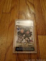 Front view of Sidney Crosby rookie card graded BCCG Gem Mint 10 in protective casing on wooden floor.