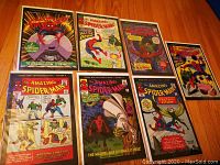 Seven Amazing Spider-Man special edition comics laid out on a wood surface showing front covers with clear protective sleeves.