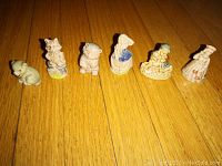 Front view of six Wade Red Rose nursery rhyme figurines arranged on wooden floor showing individual characters and colors.