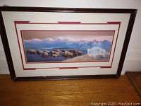 Full view of the framed colorful print of bison in plains and mountains.