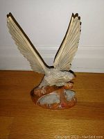Front side view of hand-carved wooden hawk sculpture with wings spread, perched on hardwood base with earth tone painting.