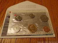 Sealed blister pack containing six 1990 Canadian coins laid on wooden surface
