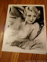 Black and white 8x10 photo of Joan Blondell lying down with handwritten autograph: "Very truly yours, Joan Blondell".