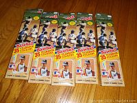 Five unopened 1984 Topps Baseball Yearbook Sticker boxes arranged in line on wood floor. Each box advertises 35 stickers and features Nolan Ryan in Oakland Athletics uniform.