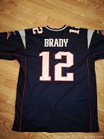 Back of navy blue jersey showing 'BRADY' and number 12 in white with red outline.