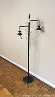 Full view of the metal floor lamp showing height, two hanging lights, and scroll metalwork.