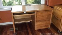 Full view of the wooden computer desk showing the structure, drawers, shelf, and legs.