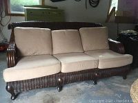 Front view of dark brown wicker sofa with tan cushions in a garage setting