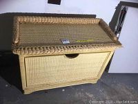 Wicker storage bench showing front and top view with woven wicker construction and pull-down front.