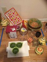 Full lot overview showing pottery pieces, pizza plates, glass trifle dish, plastic tray, and other assorted serveware items.