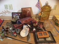 Overview of assorted picture frames, decorative items including elephant and Taj Mahal figurines, beaded table runner, ceramic basket decor, glass chess pieces, metal letter box, glass bowl, candle holders, and plated platter.