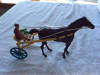 Side view of the full wind-up horse and cart toy set on a towel background.