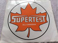 Photo of full vinyl decal showing the orange maple leaf and 'SUPERTEST ALL CANADIAN' wording, in white and black on white background.