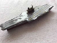Front-side view of the die cast aircraft carrier toy showing the deck and superstructure island on a carpeted surface.