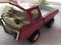 Front angle view of the vintage pink Tonka pressed steel toy truck showing clear plastic windshield, steering wheel inside, and front grille details.