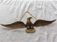 Full view of brass eagle wall hanging with wings spread wide on white background.