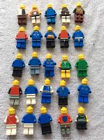 Full view of 25 LEGO minifigures arranged in rows on a surface showing various torso and leg colors.