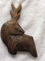Front and side view of Haida carved wood deer sculpture showing detailed carved features and antlers.