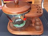 Side angle showing teak wood humidor base with circular slots and glass globe with pheasant decor, teak lid with knob handle.