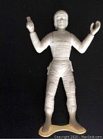Full view of the white plastic 1960s spaceman toy figure against a dark background.