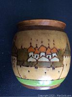 Photo of the wooden snuff box showing the hand-painted Russian motif of a Kremlin fortress with orange onion domes and red roofs on a beige background.