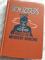 Front cover of vintage 1950 Roy Rogers storybook showing orange hardbound with black and white skeleton graphic and title text.