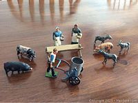 Overview of all pieces arranged on table showing farm worker figures, feeding trough, pig, goats, and farmer with cart