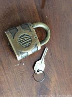 Early Yale brass padlock and original key with ring shown together on wooden surface.