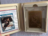 Front view of presentation case open showing bronze metal card of Wayne Gretzky and certificate of authenticity card on left.