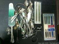 Overall view of silver and plated flatware, small collectible items, and boxed pens and calligraphy nibs.