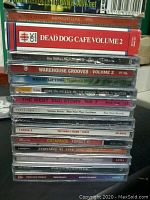 Photo showing a stack of various music CDs with visible titles such as From Manchester With Love, Dead Dog Cafe Volume 2, The Wallflowers, Warehouse Grooves Volume 2, and others.