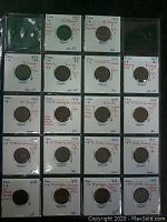 Photo showing 18 individually held Canada 1 Cent coins dated 1947 and 1948 with handwritten notes about condition and varieties on holders.