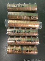 Six rolls of Canadian pennies stacked, labeled with years 1982, 1988, 1992, 1998, 1999, and 2002 along with condition notations on some rolls.