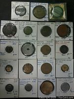 Photo showing 19 US tokens from the 19th and 20th century in white cardboard holders with handwritten descriptions and prices.