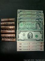 Photo showing six rolls of Canadian pennies and several Canadian and US banknotes arranged side by side.