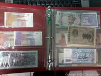 Photo showing multiple banknotes in clear plastic sleeves within an album, featuring banknotes from Singapore and various Asian countries.