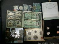 Overview of coins and banknotes showing 25 cent Dominion of Canada banknotes, 1967 and 1968 one dollar bills, and various coins including shinplasters and large cents.