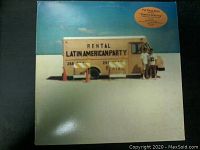 Front cover of the vinyl EP showing a rental truck with 'Latin American Party' text and two people beside it on a beach.